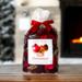 Irish Twins Apple Cinnamon Potpourri bag with red ribbon, against a fireplace and snow-covered pine tree.